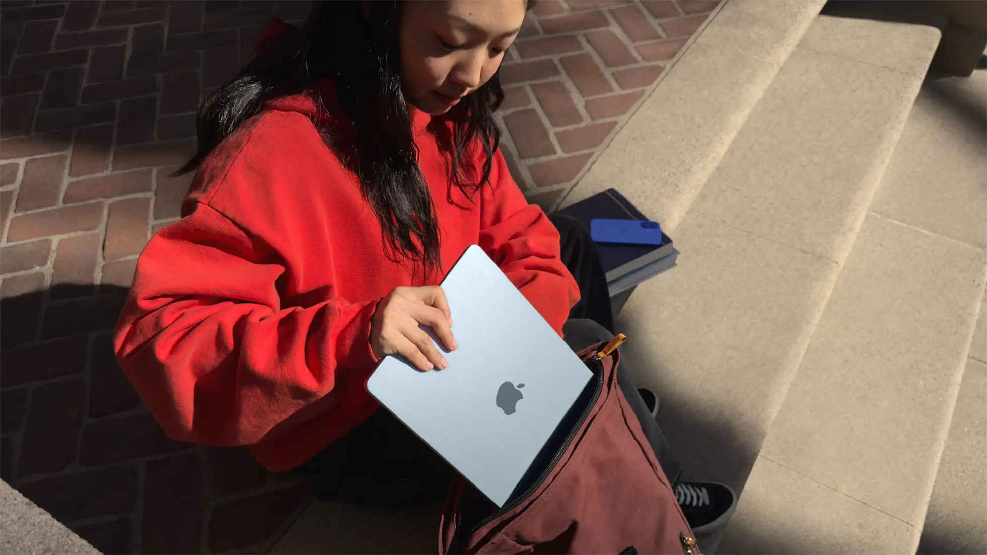 A student putting her mac book in her bag