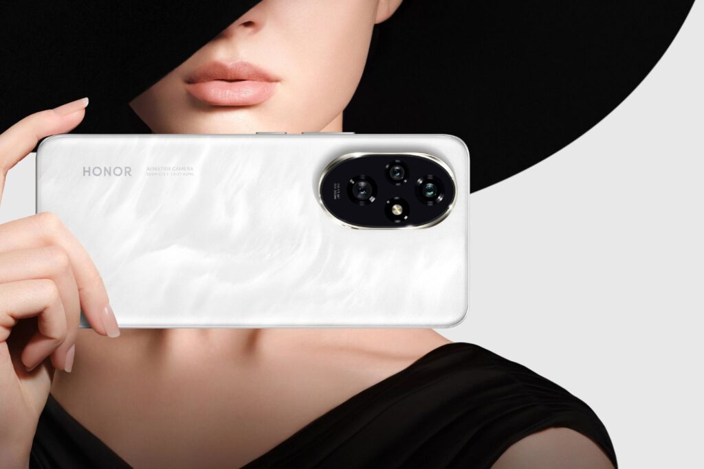 White Honor smartphone showing textured back panel with oval triple-camera module, held horizontally in hand